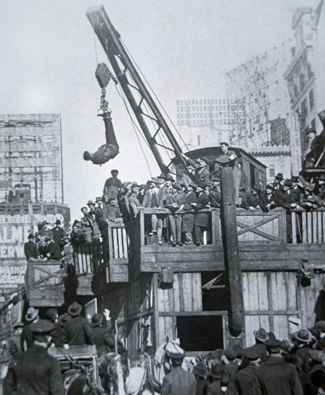 Houdini entkommt aus einer Zwangsjacke, während er an einem Kran in New York City hängt von American Photographer