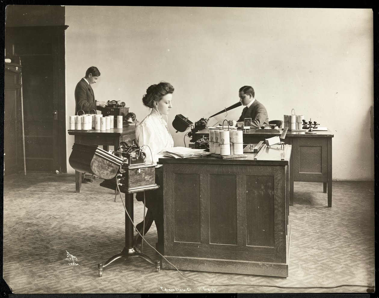 Innenansicht einer Frau, die von einem Diktiergerät tippt, und eines Mannes, der in ein anderes diktiert, bei der Edison Phonograph Co., West Orange, New Jersey, 1903 von Byron Company