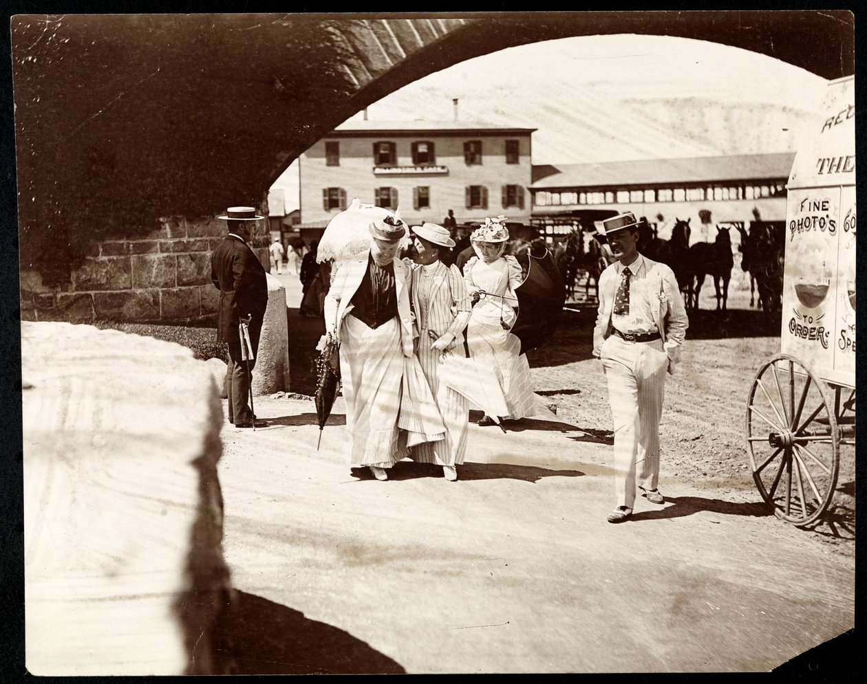 Drei Frauen und ein Mann spazieren am Narragansett Pier mit dem Wagen eines Wanderfotografen, Rhode Island, 1891 von Byron Company