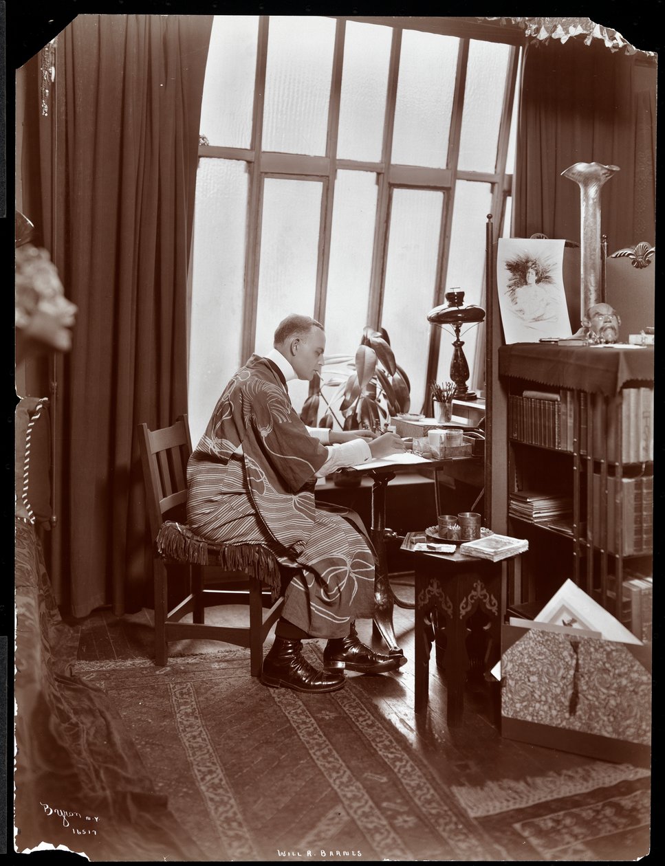 Will R. Barnes in einem Gewand, sitzend an seinem Schreibtisch in seinem Studio, 1903 (Silbergelatineabzug) von Byron Company