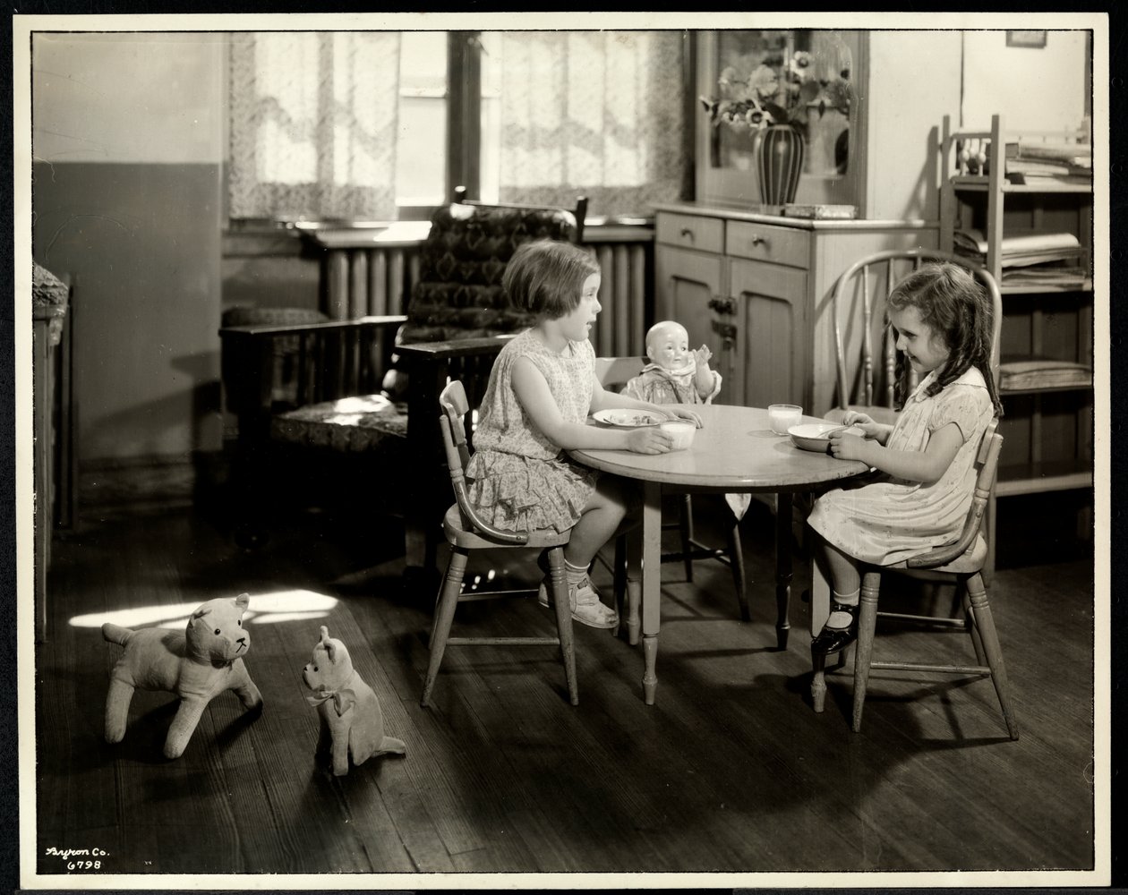 Zwei blinde sehbehinderte Mädchen essen an einem kleinen Tisch mit Puppe bei der New York Association for the Blind, 111 East 59th Street, New York, 1933 (Silbergelatineabzug) von Byron Company
