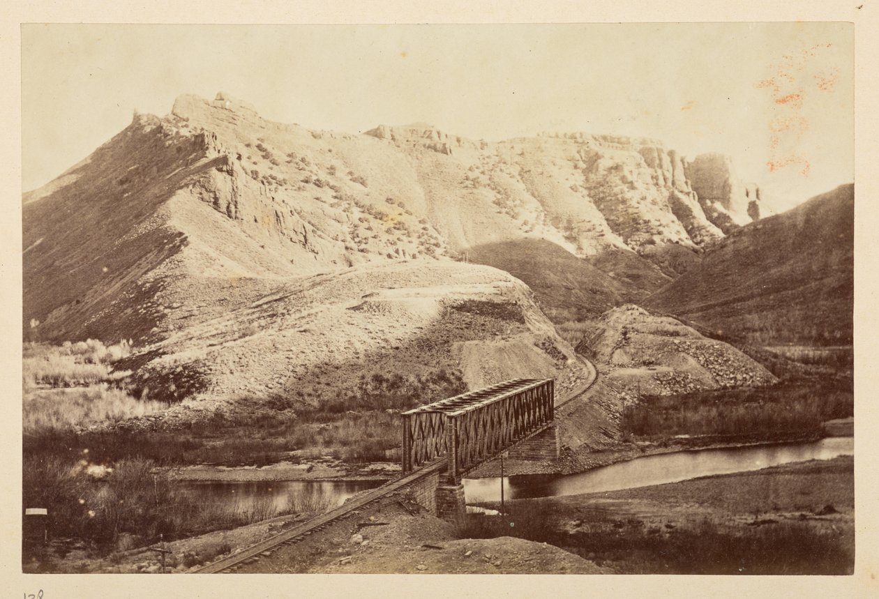 Ansichten der Pazifikbahn, Eisenbahnschienen, die einen Fluss auf einer Fachwerkbrücke überqueren, mit Bergen dahinter von English Photographer