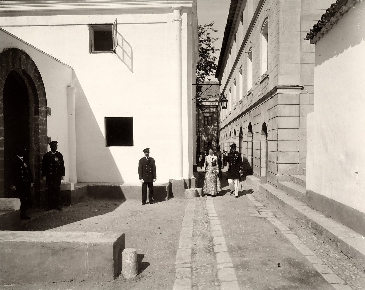 Männer in Uniform begleiten eine elegant gekleidete Frau zur Kirche des Bauernhofs Lo Zucco, Sizilien, 1900 von Eugenio Interguglielmi