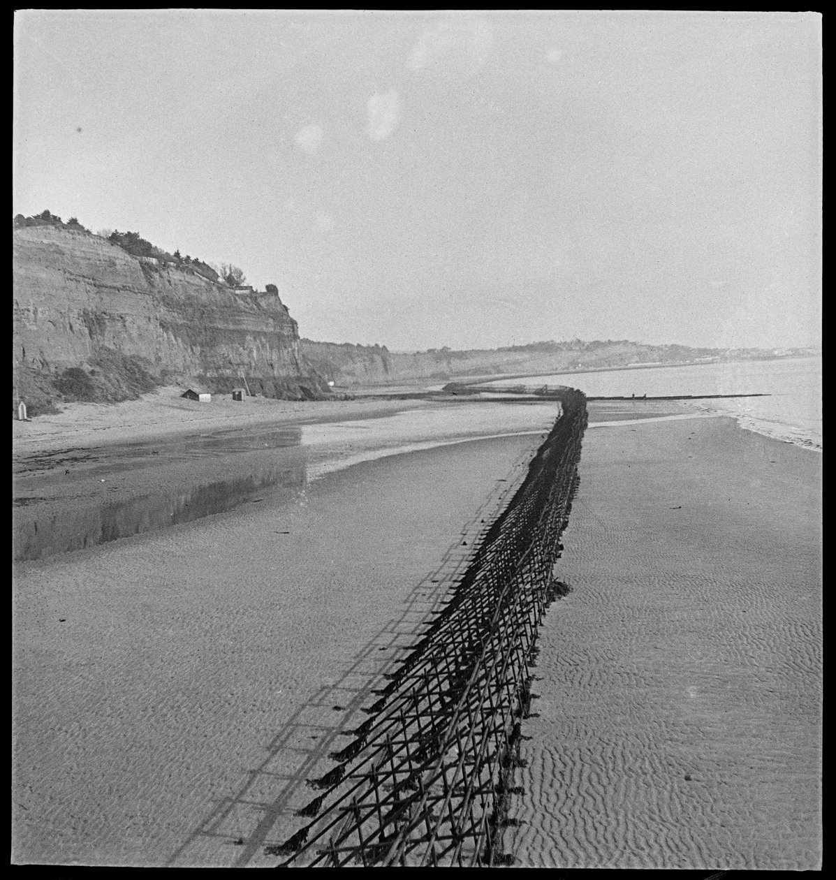 Blick nach Nordosten vom Luccombe-Ende des Shanklin Beach, mit Admiralty-Gerüst (Hindernis Z.1) entlang der Küste von George R. Long