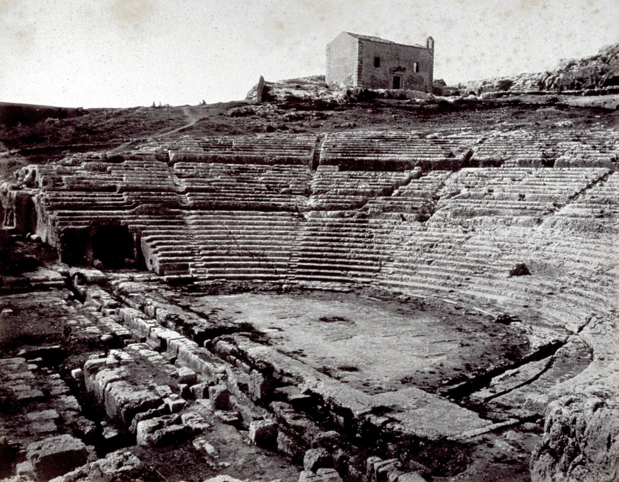 Die Überreste des griechischen Theaters in Syrakus im Monumentalpark der Neàpoll. Im Vordergrund die halbkreisförmige Orchestergrube und die Cavea von Giorgio Sommer