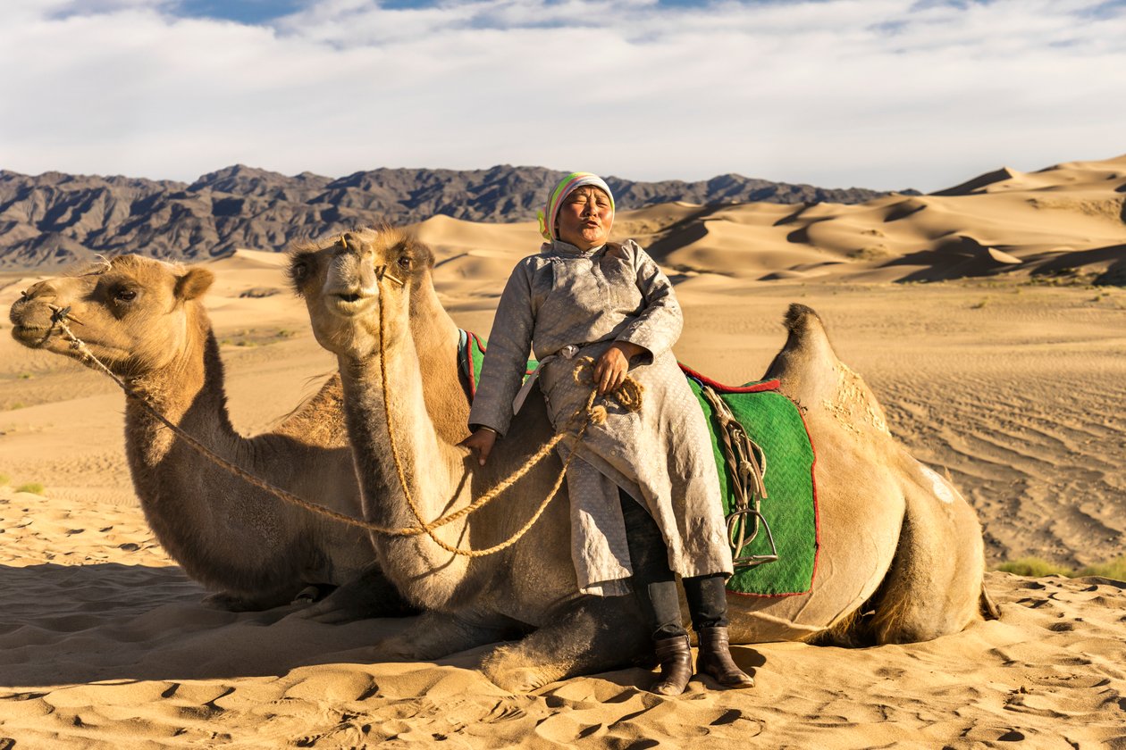 Eine Frau ruht sich mit Kamelen in der Süd-Gobi-Wüste, Mongolei aus, 2015 (Foto) von Ira Block