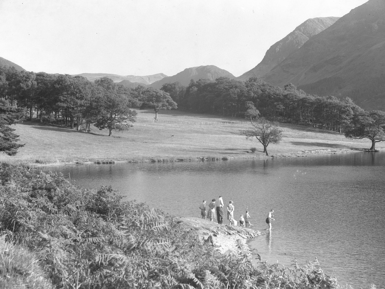 Eine Familie am Rand des Sees angelt und schaut ins Wasser von Joseph Hardman