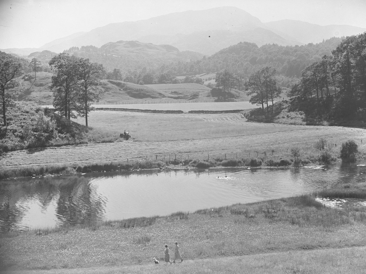 Frauen schieben Baby im Kinderwagen am Fluss entlang durch eine Wiese mit Menschen, die im Fluss schwimmen, und Bauer, der Traktor auf Feldern im Hintergrund arbeitet von Joseph Hardman