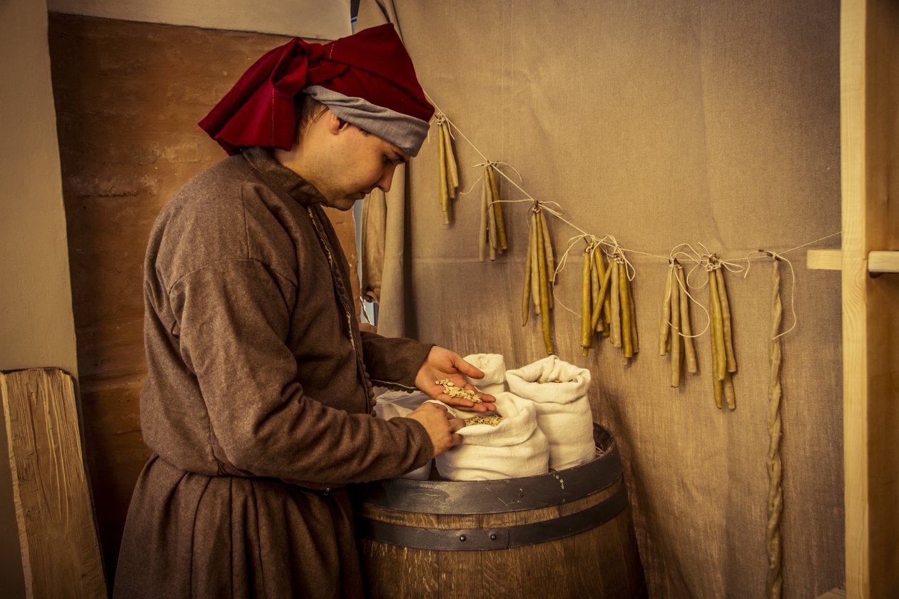 Historische Nachstellung: Kerzen und Säcke mit Weizen, Roggen und Gerste in der Apotheke von Diotaiuti, Imola, Italien, Mitte des 14. Jahrhunderts von Unbekannt Unbekannt