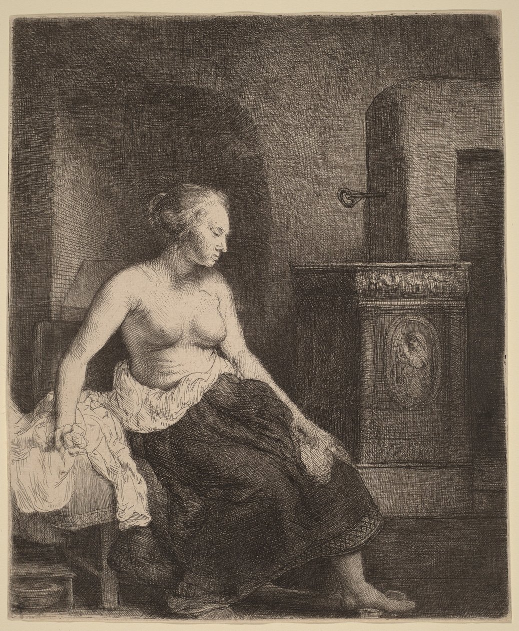 Frau sitzt halb angezogen neben einem Ofen von Rembrandt van Rijn