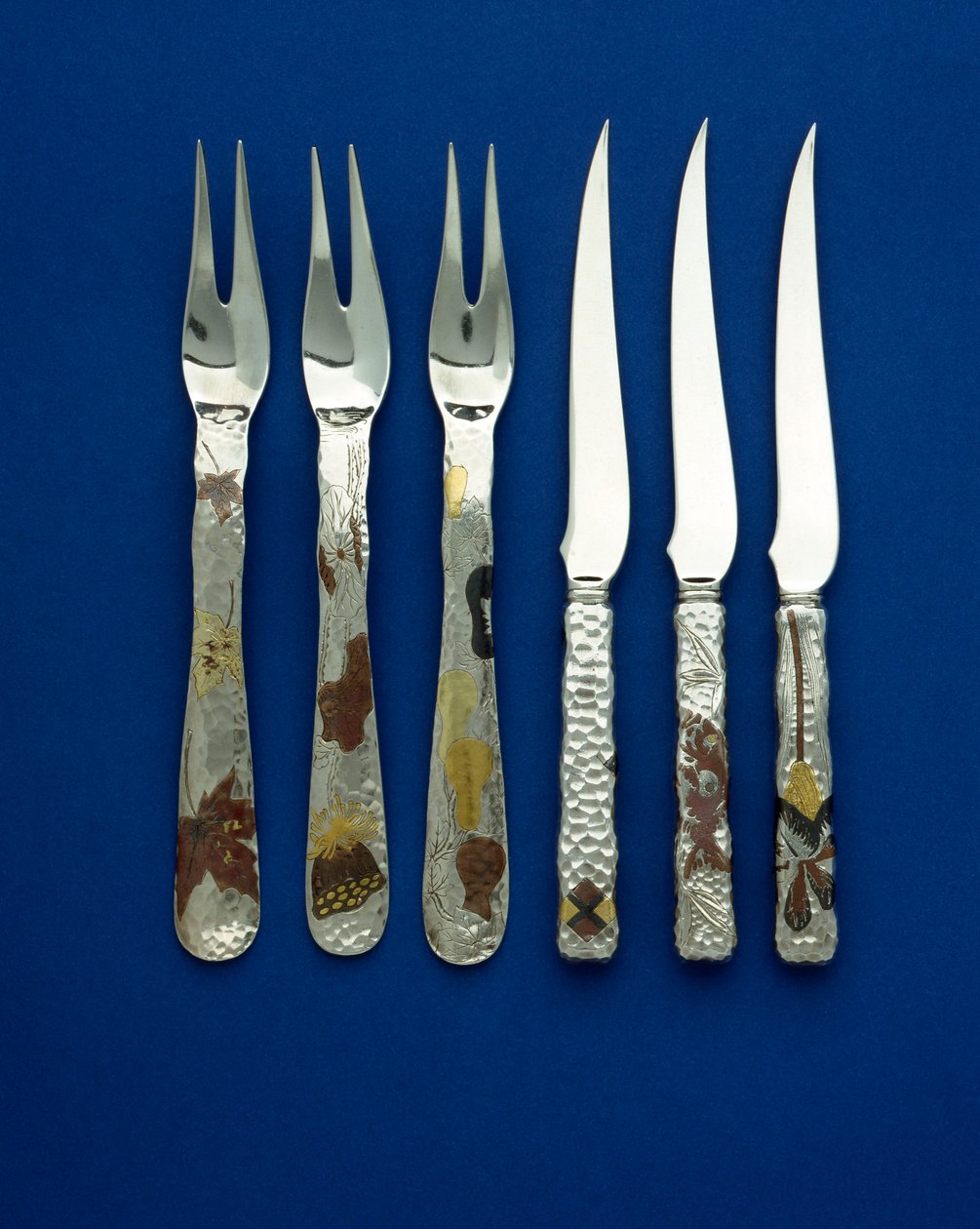 Teil eines feinen und seltenen Sets von 36 Dessertmessern und -gabeln, die punktgehämmerten Griffe eingelegt mit patiniertem Kupfer und verschiedenfarbigem Gold, mit gravierten Details von verschiedenen Blumen-, Tier- und geometrischen Designs, ca. 1880 von Tiffany and Company