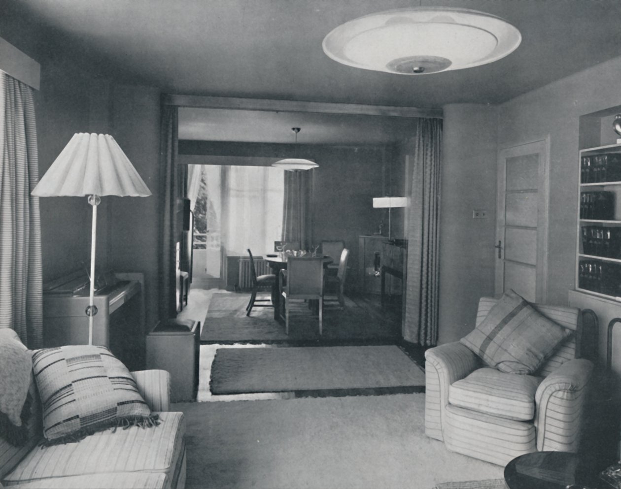 Ess- und Wohnzimmer, nur durch schwere Vorhänge in einem attraktiven modernen Gewebe getrennt, 1942 von Unbekannt