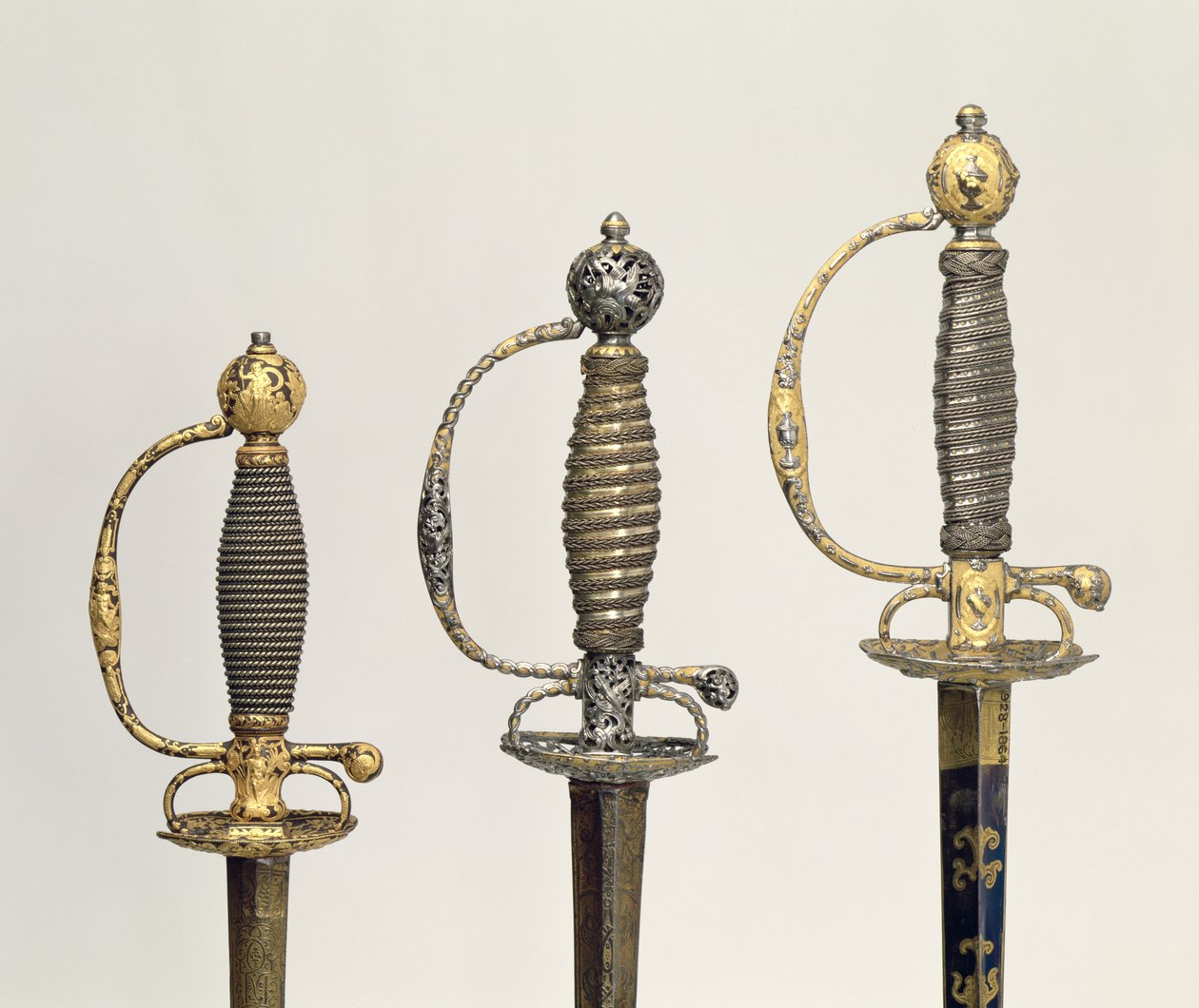 Griffe von drei französischen Schwertern: einer aus Stahl, gebläut und mit Goldgravuren verziert, um 1730; einer aus Stahl, durchbrochen und gemeißelt und der Grund aus mattiertem Gold, um 1760; einer aus gemeißeltem Stahl, gr von Unbekannt Unbekannt