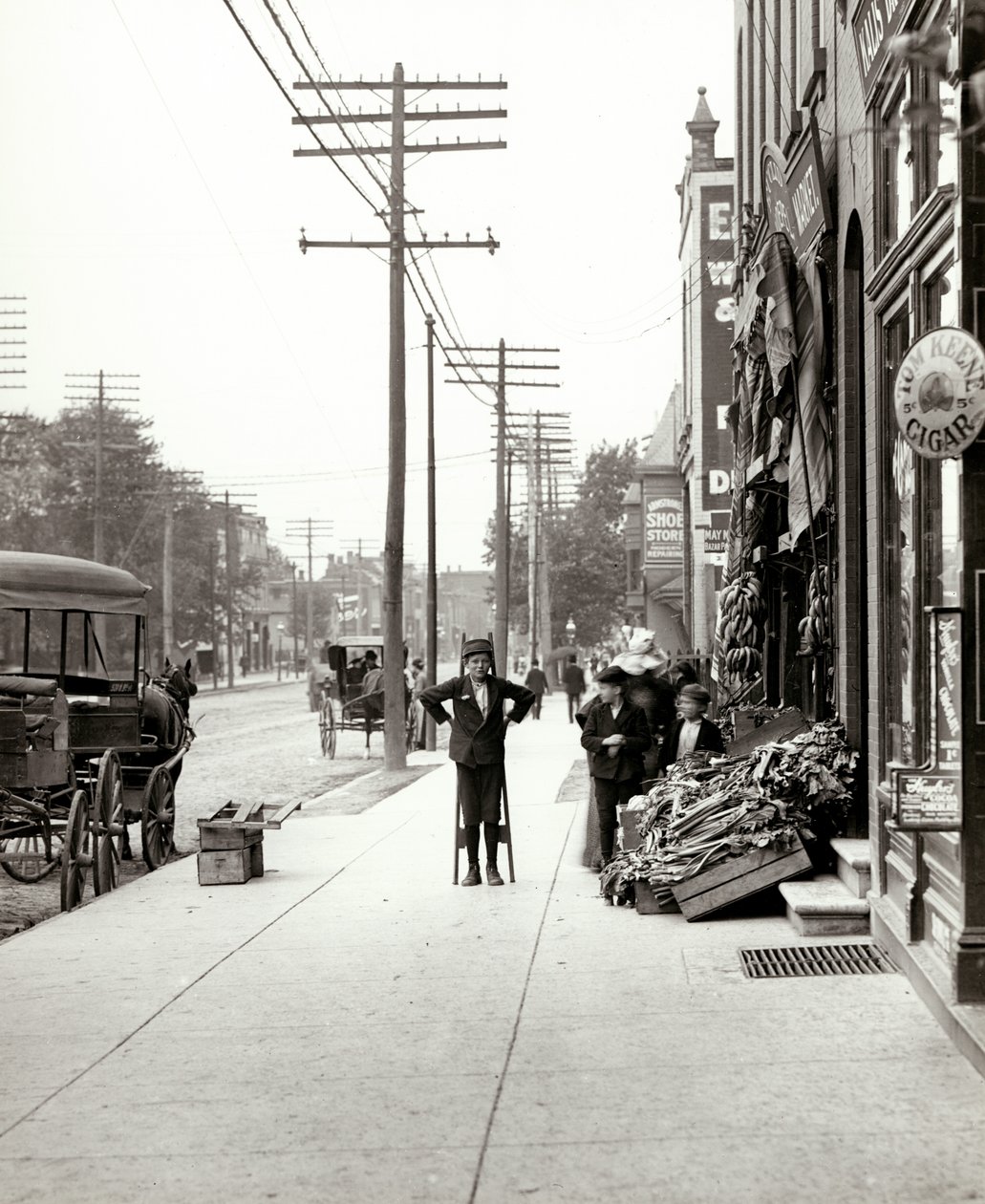 Ein Junge mit Stelzen vor dem F.J. Voepel Markt in der Easton Avenue 4874, an der südöstlichen Ecke von Easton und Euclid. Easton war später als Dr. Martin Luther King Drive bekannt von Unknown