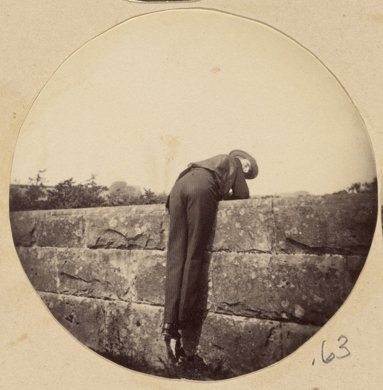 [Mann mit Hut über eine Steinmauer gebeugt] von Unknown artist