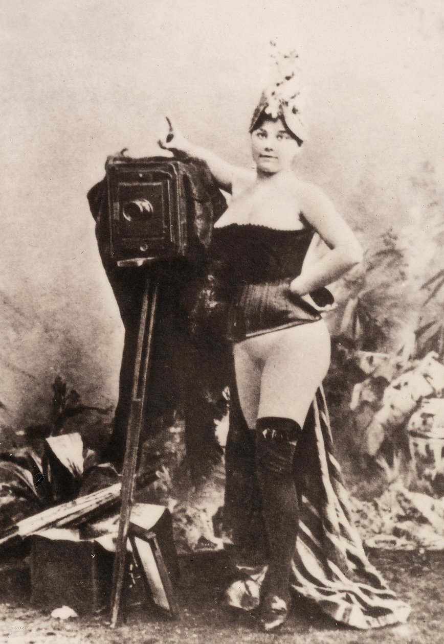 Porträt einer teilweise nackten Frau, die sich auf eine antike Kamera lehnt von Unknown photographer