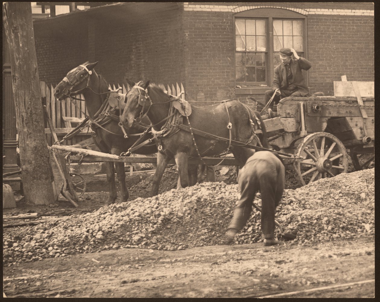 Horizontales Schwarz-Weiß-Foto eines pferdegezogenen Wagens auf einer Baustelle. Ein Mann schaufelt Erde und Steine, während ein anderer den Wagen fährt von William G. Swekosky