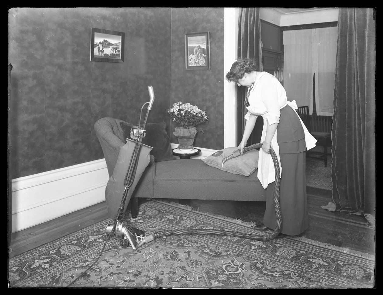 Unidentifizierte Frau demonstriert die Verwendung des Polsteraufsatzes des Apex-Staubsaugers, ca. 1913-14 von William Davis Hassler