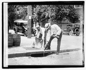 Zwei Männer gießen Schnaps in einen Regenabfluss, 8. Juli 1921 von American Photographer