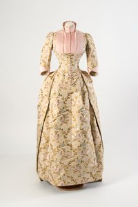 Kleid aus hellbrauner Seide mit einem Design aus mauve, blauen und gelben Blumen und grünen Blättern, hellrosa gerippte Seidenmieder und Manschetten von American School