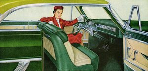 Frau sitzt auf dem Fahrersitz eines Coupés aus den 1950er Jahren