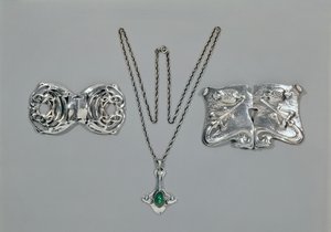 Silberschmuck entworfen für Liberty. Von links nach rechts: Taillenspange mit verschlungenem keltischem Design, 1904. Anhänger und Kette mit Cabochon-Schliff Chrysopras. Taillenspange mit Repousse-Design auf gehämmertem