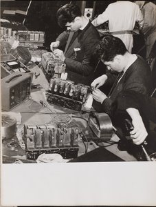[Zwei junge Männer in Blazern arbeiten an Radios] von Arnold Eagle