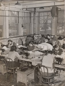 [Frauen sitzen an Schreibtischen und arbeiten an Nähmaschinen] von Arnold Eagle