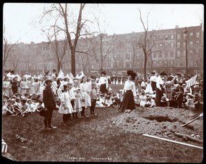 Erwachsene und Kinder mit Fahnen stehen um ein frisch gegrabenes Loch für eine Baumpflanzung am Arbor Day im Tompkins Square Park, New York, 1904