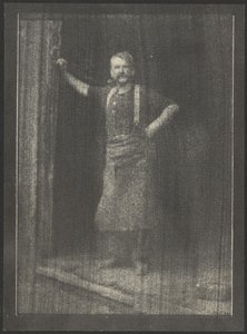 [Schmied steht in der Tür, Pfeife im Mund] von Doris Ulmann