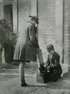 Ein junger Schuhputzer putzt die Schuhe eines Mannes auf der Straße von English Photographer