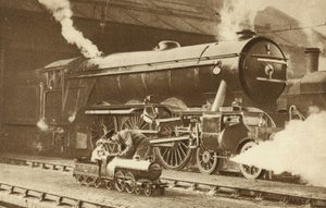 Junge reitet auf einer Spielzeug-Dampflokomotive vor dem echten Ding (s/w Foto)