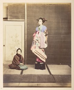 [?Geisha,] Ganzkörperporträt einer jungen Frau in erhöhten Schuhen, ihr junger Begleiter kniet neben ihr von English Photographer