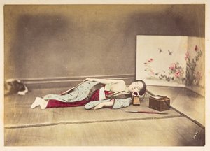 Japanische Frau schläft, Studio-Porträt einer jungen japanischen Frau, die schläft, eine Brust entblößt und mit dem Kopf auf einem Holzpolster ruhend von English Photographer