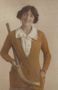 Hübsches Mädchen, im gestrickten Pullover, mit Perlenohrringen, hält einen Hockeyschläger (Foto) von English Photographer