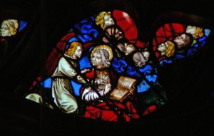 Das westliche Rosenfenster zeigt eine Szene aus dem Buch der Offenbarung: Köpfe der sieben Donner (in einer blauen Wolke) und Johannes wird verboten zu schreiben (10:3-5).