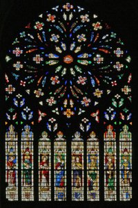 Fenster w237, das westliche Rosenfenster, Darstellung des Lammes der Apokalypse (20. Jh.) im Zentrum, umgeben von 12 Engelmusikern; Wappen, darunter Montmorency-Laval, Bertrand Duguesclin und Oli