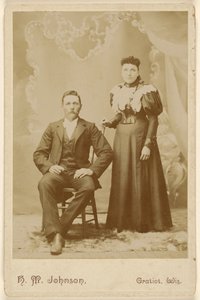 [Unbekanntes Paar: Mann mit Schnurrbart sitzend, Frau stehend] von H. M. Johnson