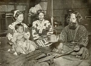 Ainu-Mann und -Frauen zu Hause, 1910