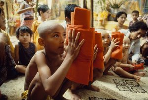 Ein Junge mit rasiertem Kopf erhält seine Mönchskleidung. Mandalay, Burma.
