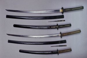 Oben: ein Katana, japanisches Schwert und seine Scheide, Wakizashi, japanisches Kurzschwert in seiner Scheide, kleiner Kokatawa-Dolch in derselben Scheide. Alle drei aus dem 18. Jahrhundert. Die unteren aus dem 17. Jahrhundert