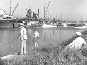 Ein Mann und ein Junge angeln in Glasson Dock, während eine Frau im Hintergrund zusieht, verschiedene Boote vertäut von Joseph Hardman