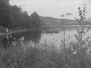 Mann angelt in einem Boot auf Esthwaite Water und zwei Mädchen am Ufer