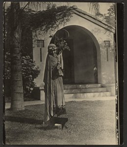 Florence im Kostüm mit Pflanze vor dem Haus von Louis Fleckenstein