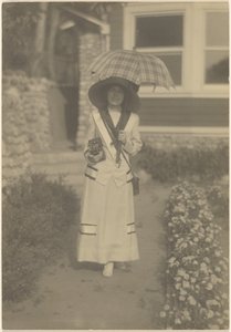 [Frau im Vorgarten mit Kamera und kariertem Regenschirm] von Louis Fleckenstein