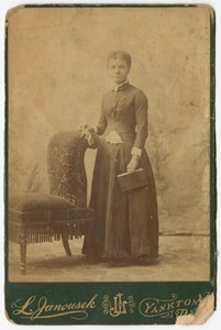 Fotografie einer Frau, die neben einem Stuhl steht und ein Buch hält, spätes 19. Jahrhundert