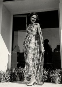 Model trägt ein langes Kleid mit Blumenmuster, kreiert von der Couture-Haus "Graldi". Der Artikel wird durch einen Mantel aus demselben Stoff ergänzt. von Luis Bogino