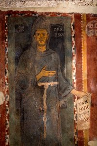 Darstellung des Heiligen Franziskus von Assisi (1181-1226). Dies ist sicherlich die erste Darstellung des Heiligen, die zu Lebzeiten ausgeführt wurde, ohne Stigmata und ohne Heiligenschein. Er hält ein Papier, auf dem in Latein „Pax huic Domui“ (Frieden) g