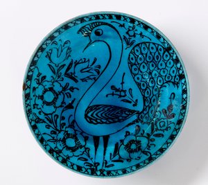 Eine persische Keramikschale aus dem 19. Jahrhundert, die einen Pfau auf einem türkisfarbenen Hintergrund darstellt