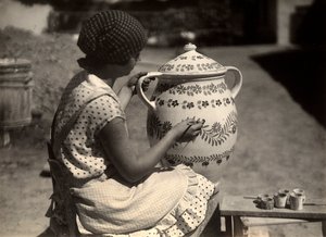 Eine ungarische Dame, die beim Bemalen einer Amphore mit Blumenmotiven porträtiert wird; daneben, auf einer kleinen Bank, die Pinsel und die Gläser mit den Farben von Rudolf Balogh